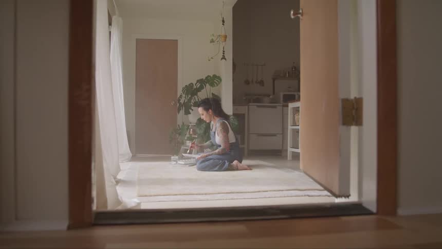 A woman sits and paints on the floor of her apartment