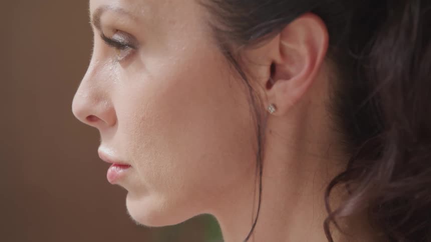 A white woman with dark hair slightly blinks her eye