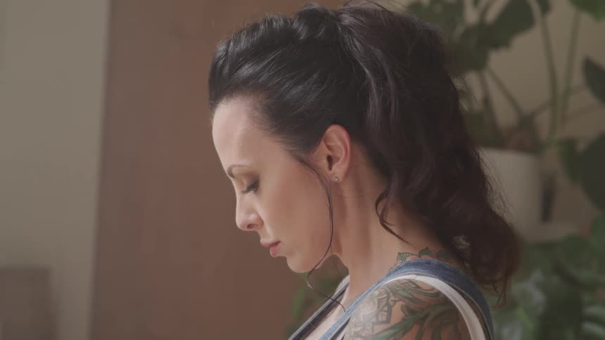 Tattooed woman looking down closes her eyes