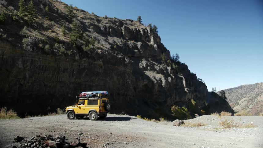 A jeep parked at the bottom of a mountain cliff