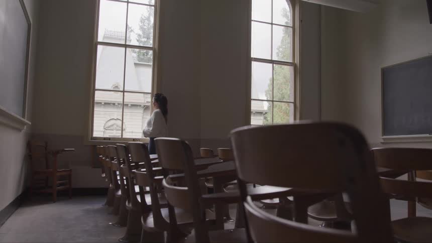 A female teacher looks out of a window in a classroom