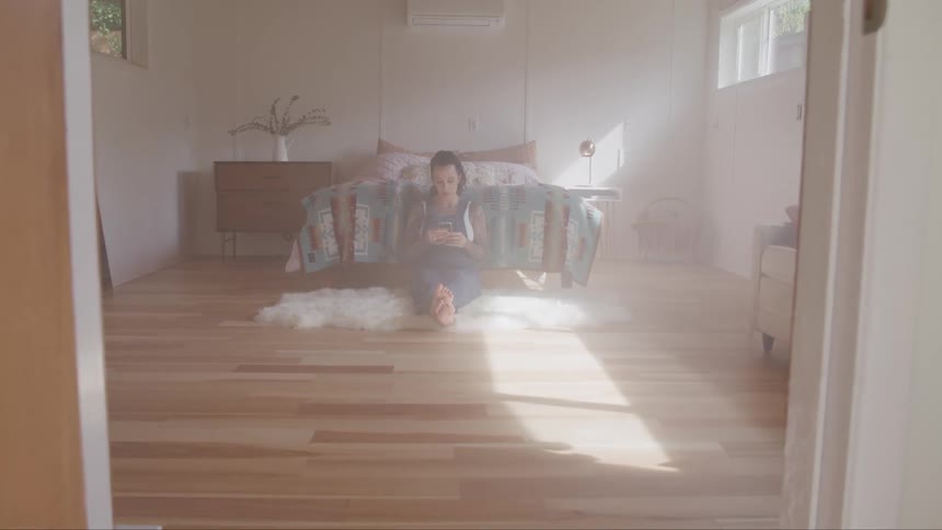 A woman sits on the floor and uses her phone