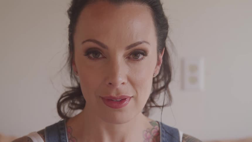Tattooed woman raises her head and stares at the camera in the living room