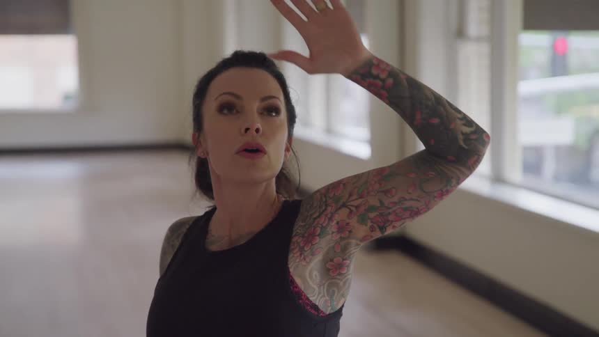 Woman with tattoos on her arms practices dance moves