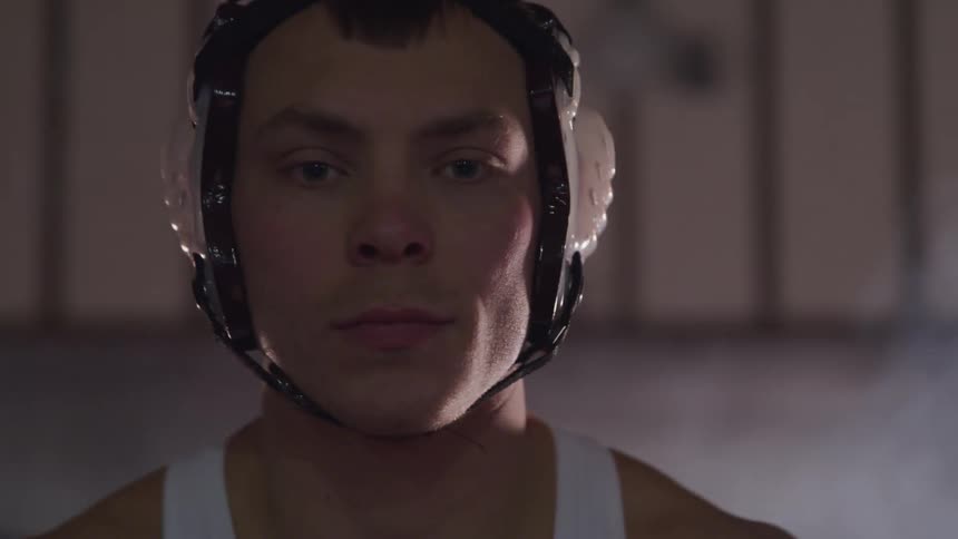 A white male wrestler twists his head in preparation for a match