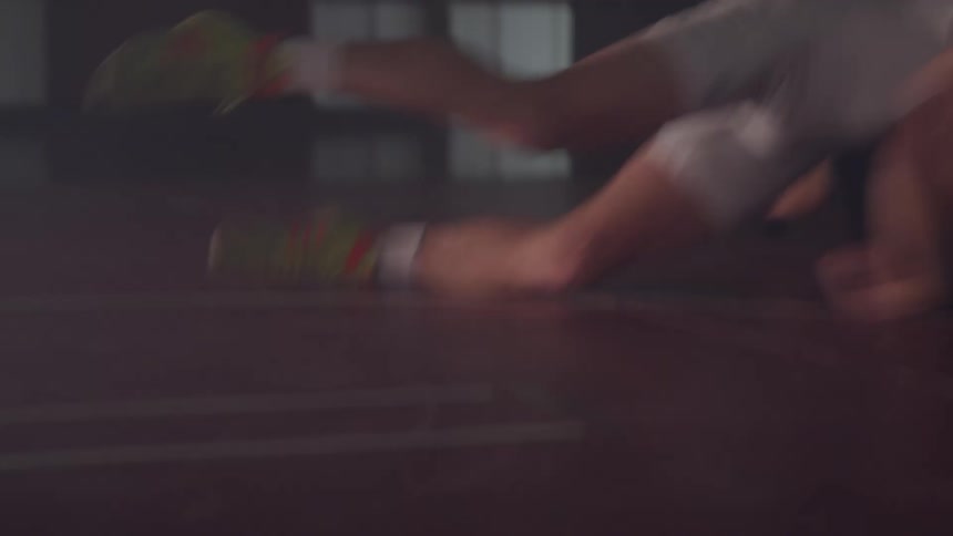 A wrestler doing a takedown on another wrestler in a dimly lit gymnasium