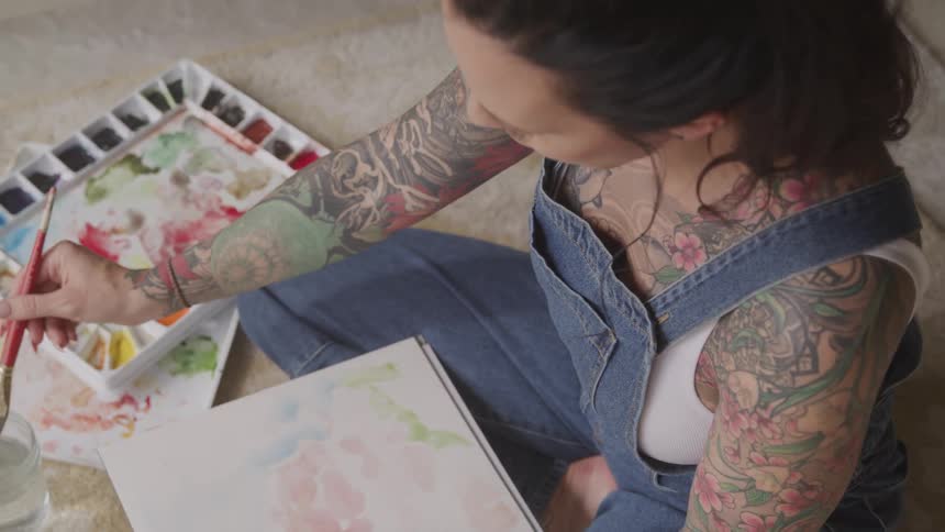 A woman sits on the floor and paints