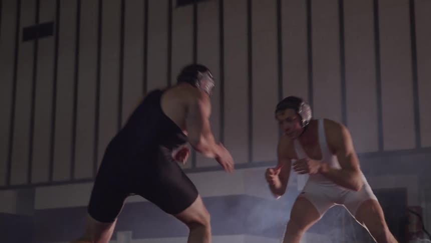 Two wrestlers ready themselves then shake hands before starting competition