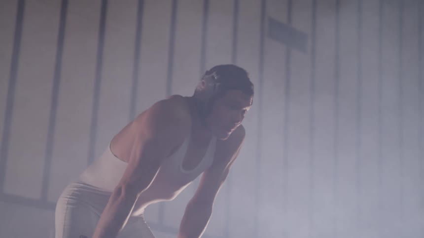 A wrestler trying to catch his breath in a room filled with mist