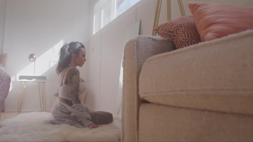 Tattooed woman sitting on the rug looks in the mirror