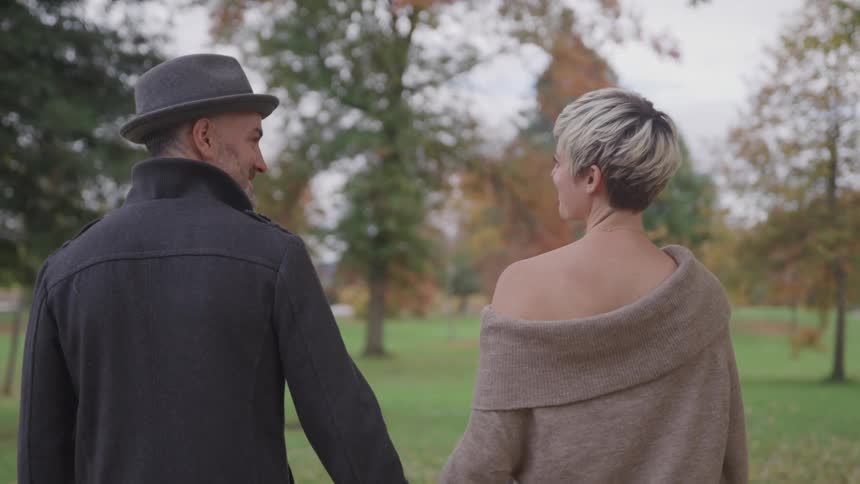 Romantic couple holding hands strolling through the park on a fall day