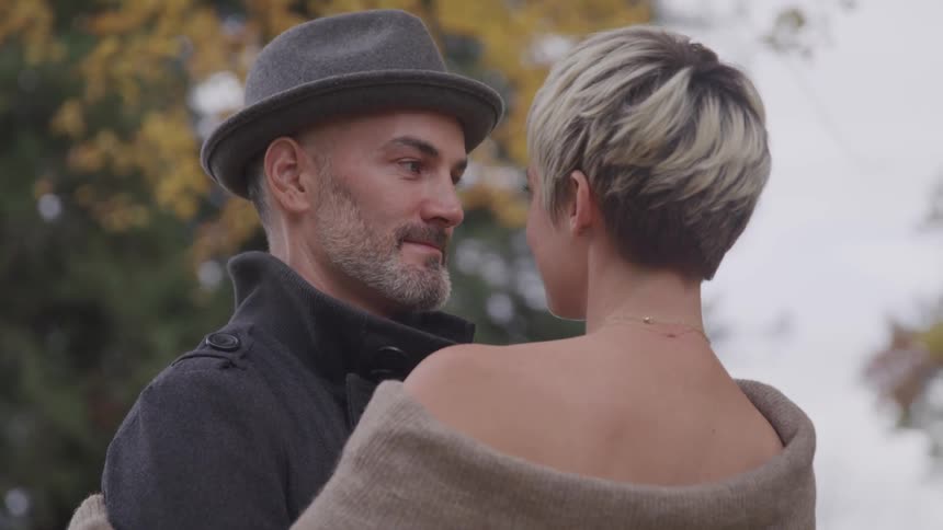 Romantic couple looking into each others eyes outdoors surrounded by trees