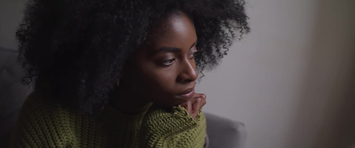 A young black woman sits with her chin in her hands