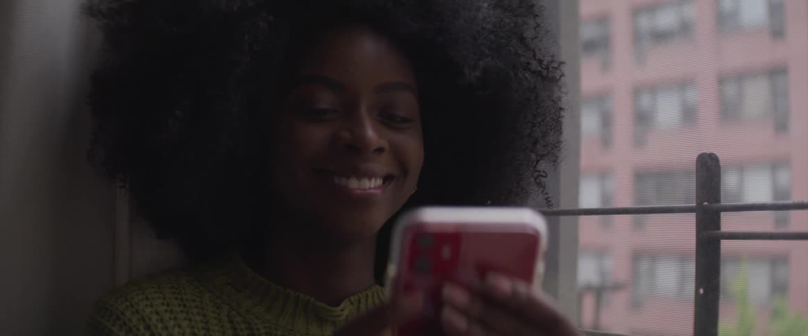 A woman smiles as she taps and texts on her phone