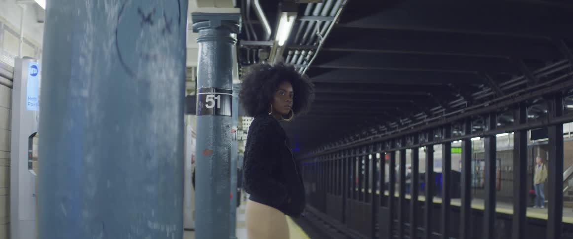 A black woman waits in the subway for a train