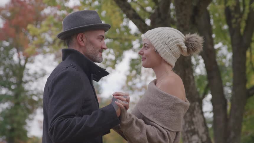 Man and woman hold hands and look at each other in the public park