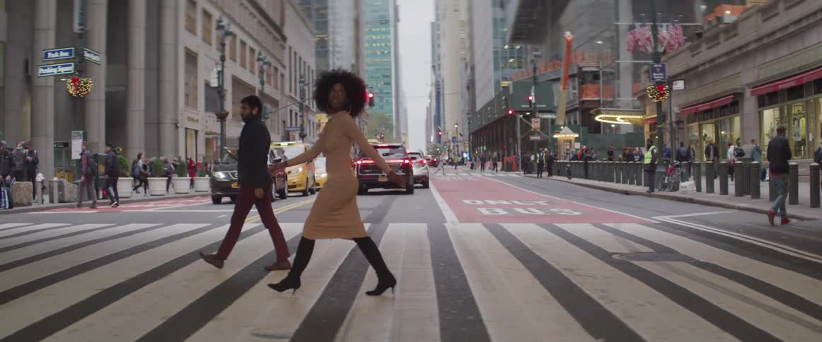 A young black woman looking back while crossing a street in a city