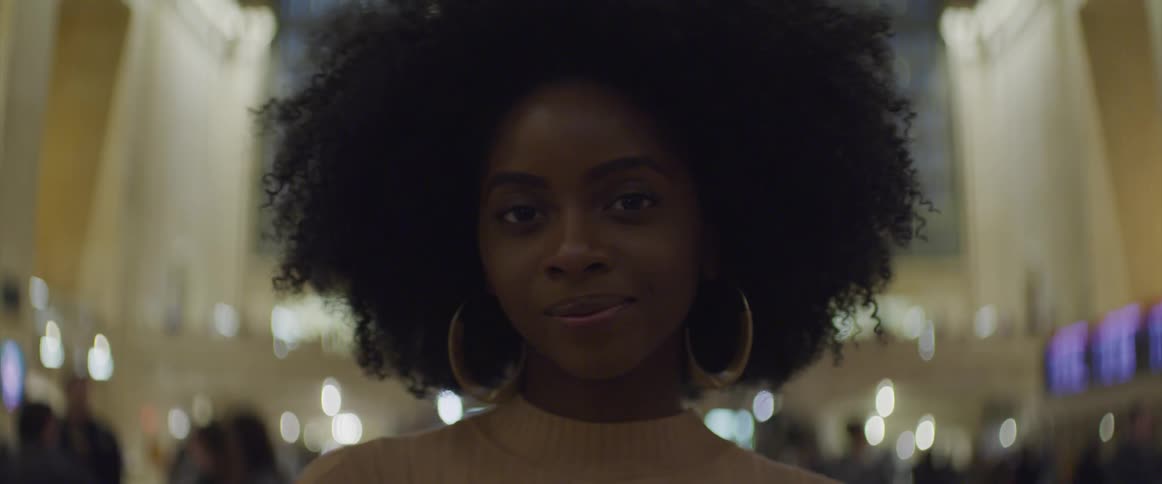Black woman wearing hoop earrings looks at the camera and smiles