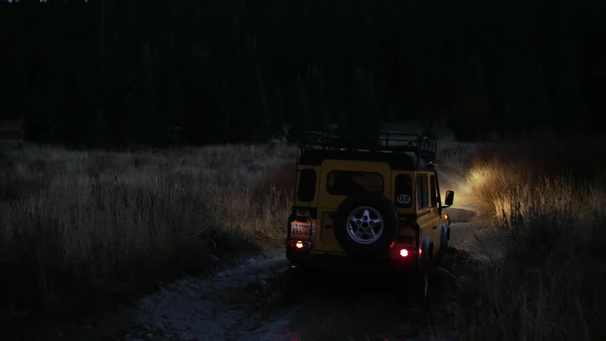 A vehicle drives in the wilderness at night