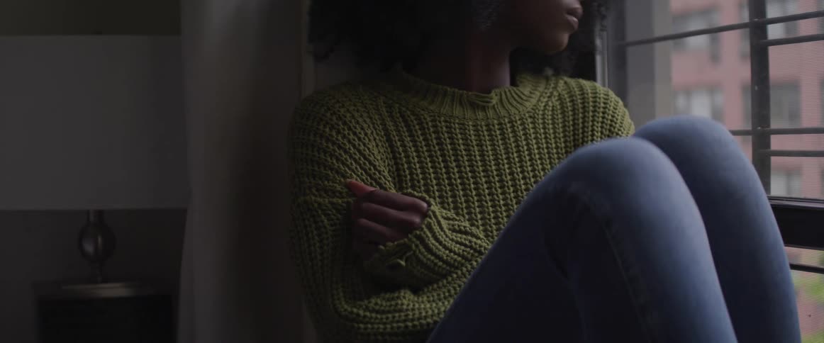 A woman sits on the window looking outside