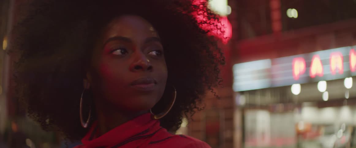 Curly hair black woman looks around in the street at night