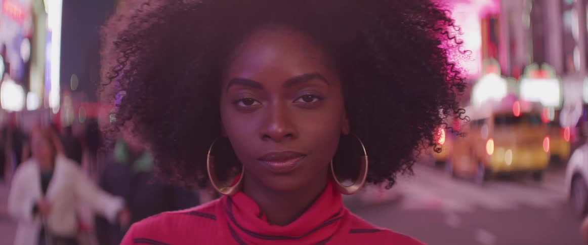 Close up of young black woman with large gold hoops standing in downtown nyc at night