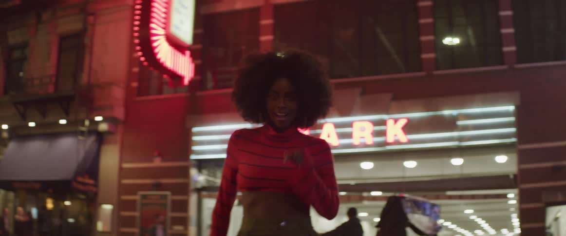 A woman dances in front of a parking garage in a city