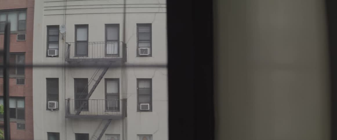 The facade of a tall building seen through the window of another building