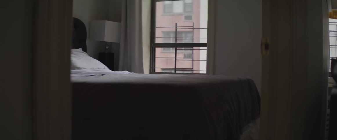 An unlit bedroom in a city apartment during the day