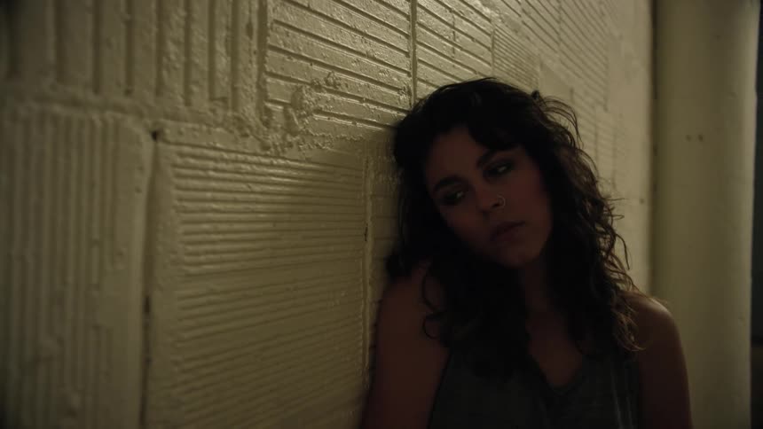 Woman leans against a wall and tilts her head back
