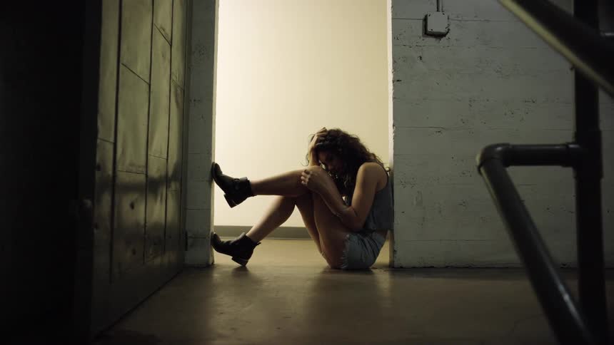 Young woman sitting on the floor in a doorway is sad or depressed