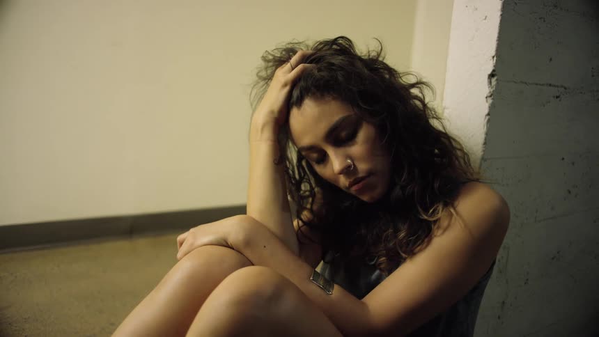 A woman sitting on the floor with her hand in her hair
