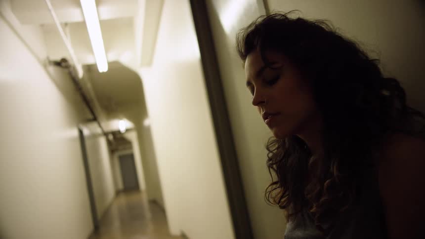 A woman is leaning against the wall in the hallway