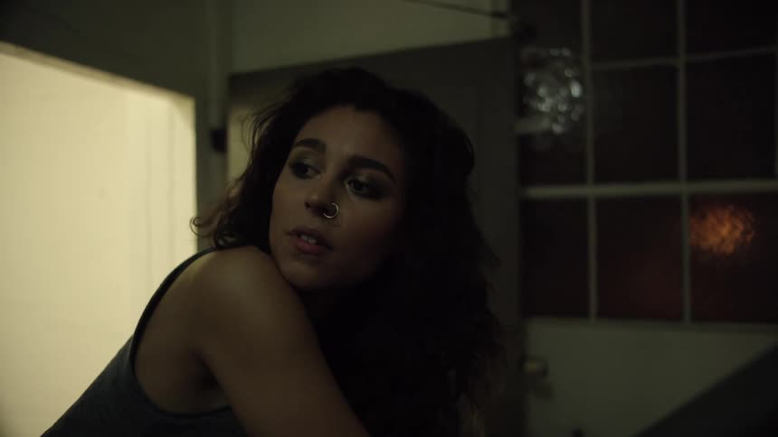 Woman inside a dark lit room in a building poses for the camera