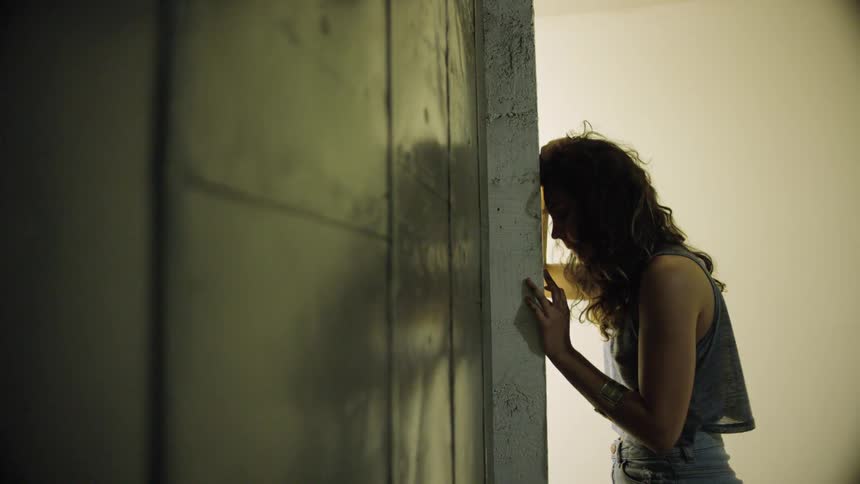 A teenager leans her head against a wall