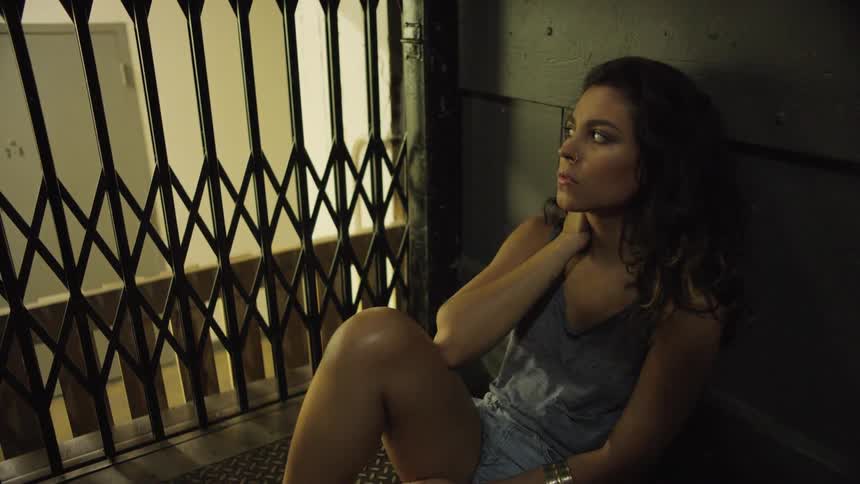 A woman sits on the ground next to a vintage elevator as it goes up