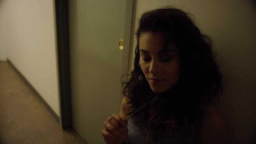A woman twirls her hair in the hallway
