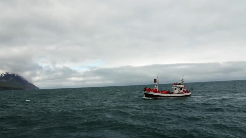 A boat is traveling across rough waters on a cloudy day