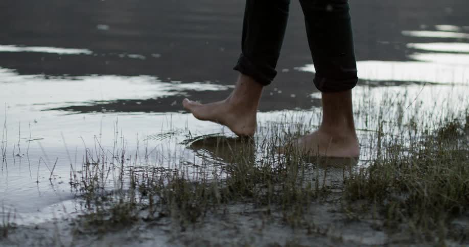Man walks into the small lake at dusk