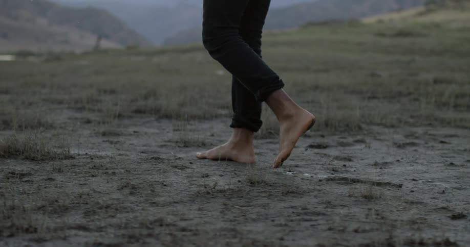 Person walking barefoot on the dirt outdoors