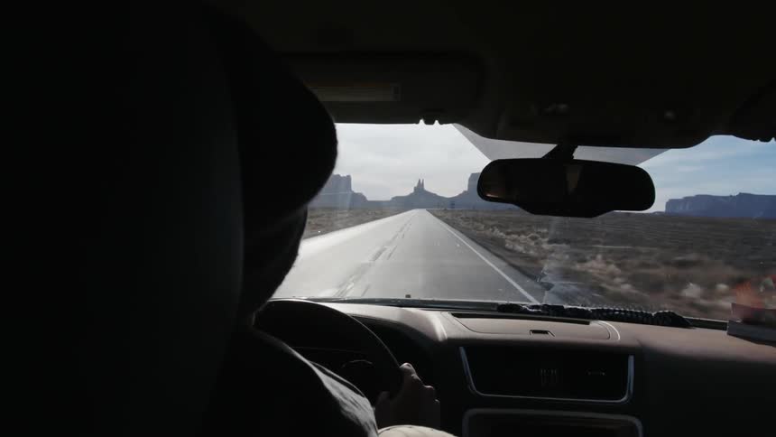 A person is driving a car down a road on a sunny day
