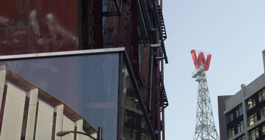 A tower with a large red letter w sits between tall apartment buildings in a city