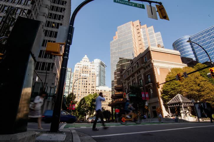 People cross on a crosswalk as vehicles pass a city intersection