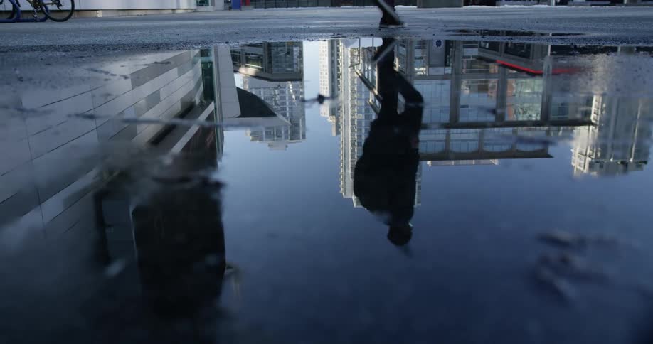 A reflection in a puddle of a person walking