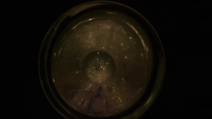 A bright round light bulb shines brightly then fades quickly with small sparks of light