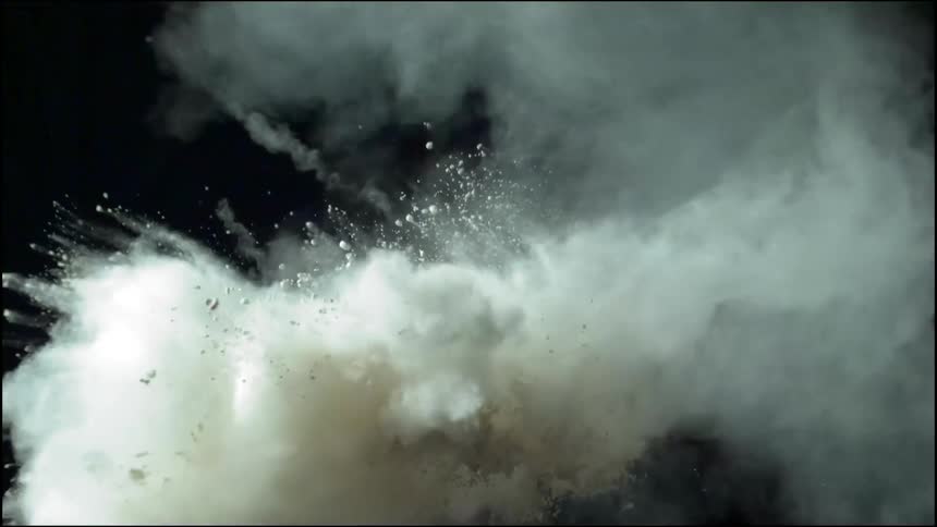 Dart flies toward and punctures black balloon throwing white dust everywhere
