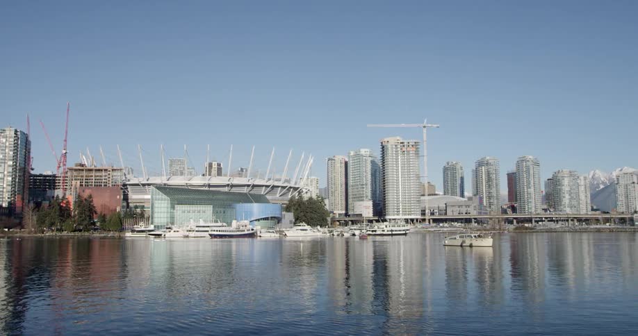 Boats and ships anchored in the harbor near the city skyline on a bright blue sunny day