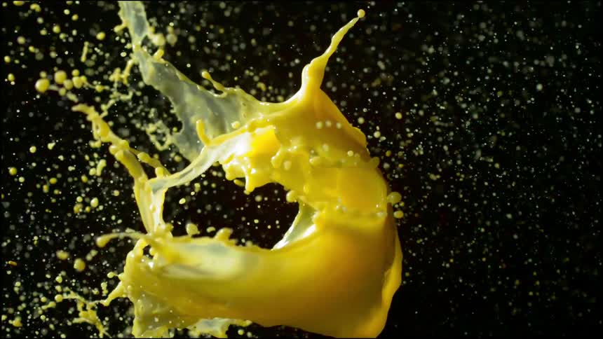 A balloon filled with yellow liquid explodes when a dart hits it