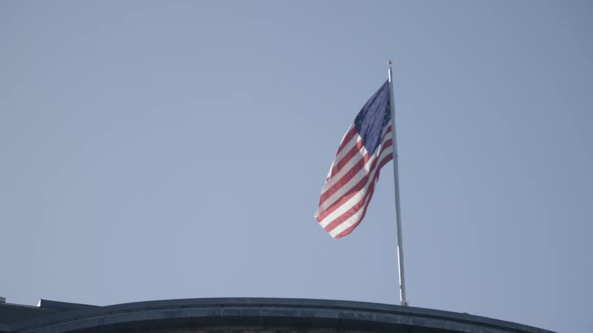 An america flag waving in the wind atop a building