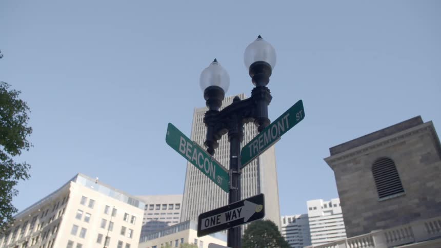 A streetlight with signs with trees and buildings in the background